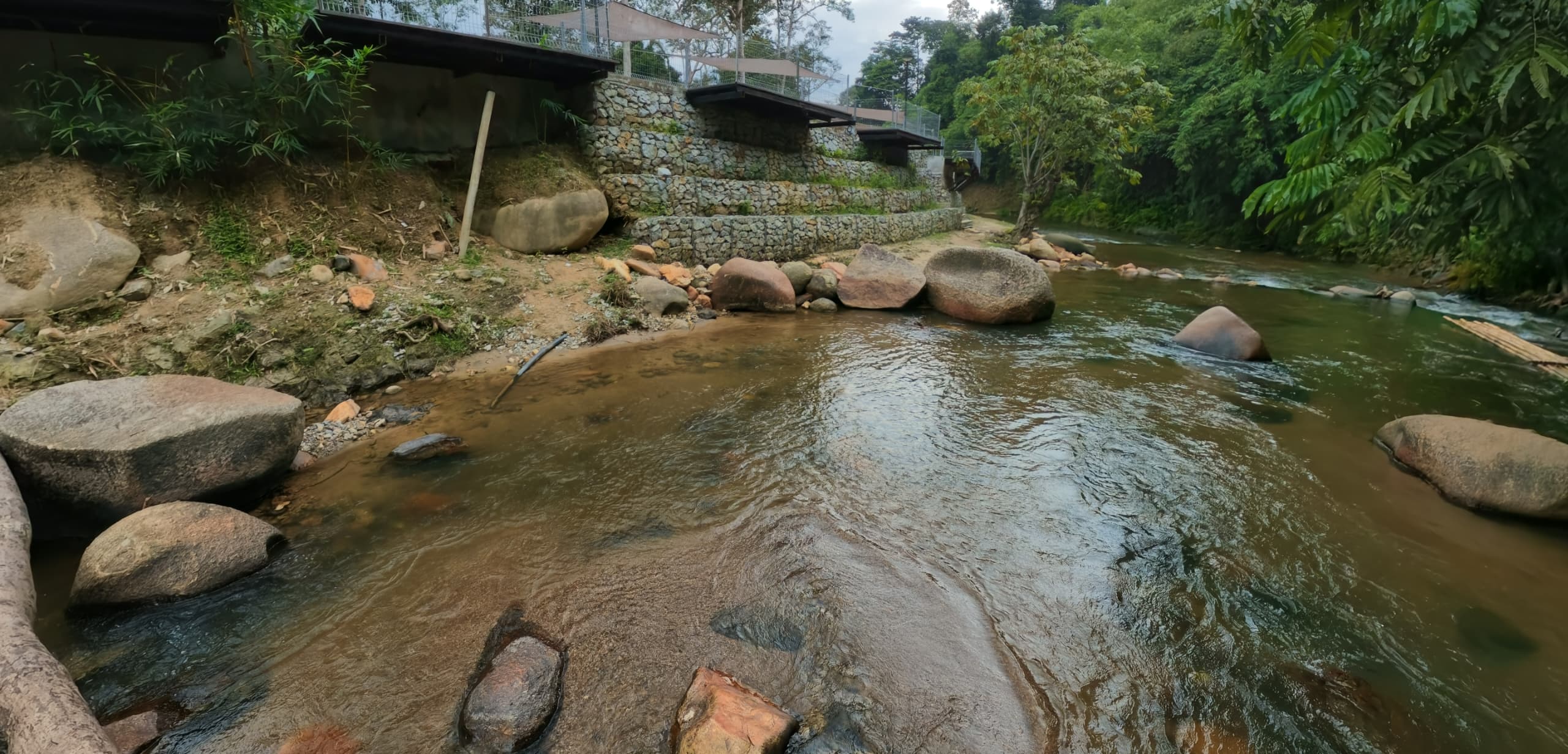 Riverbank with stone-retaining wall and large boulders